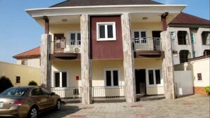 A two-story building with a central entrance, balconies on each floor, and a car parked in front. - Ivon Suites (Lagos)