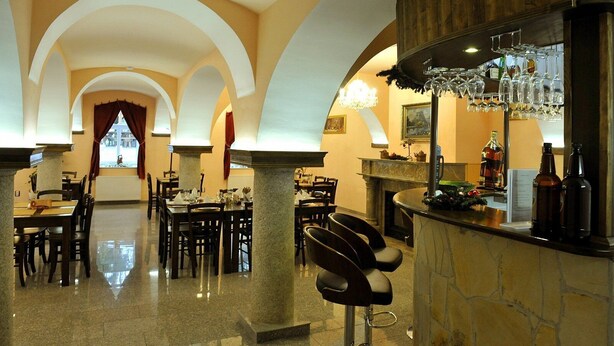 A spacious hotel lobby with a bar area, multiple dining tables, and a fireplace. - Euro Beer Spa (Depoltovice)