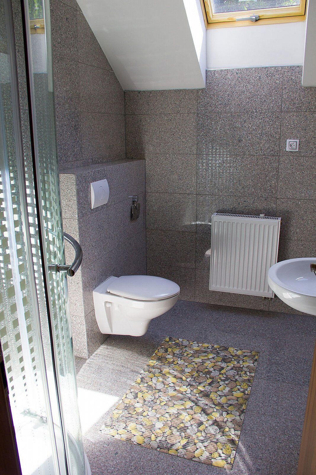 A bathroom with a toilet, sink, and shower area.