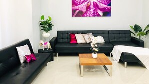 Una sala de estar moderna con un sofá negro, una mesa de centro de madera y un cuadro grande de una orquídea en la pared.