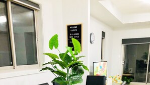Un comedor con una mesa blanca, sillas negras y una planta en maceta.