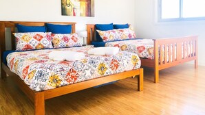 Una cama doble con ropa de cama estampada y almohadas azules, un cabecero de madera y una ventana con persianas.