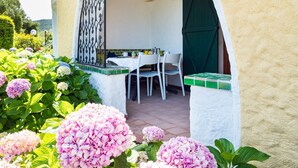 Eine Terrasse im Freien mit Tisch und Stühlen, umgeben von leuchtend blühenden Hortensien.