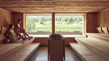 Un sauna con bancos de madera y un ventanal que ofrece vistas a un paisaje verde.