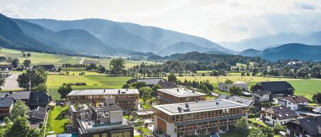 Un hôtel moderne doté d’une piscine, entouré de vastes prairies verdoyantes et avec des montagnes en toile de fond.