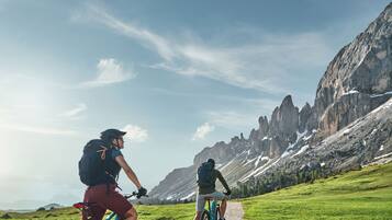 Due ciclisti su un sentiero sterrato con montagne sullo sfondo.
