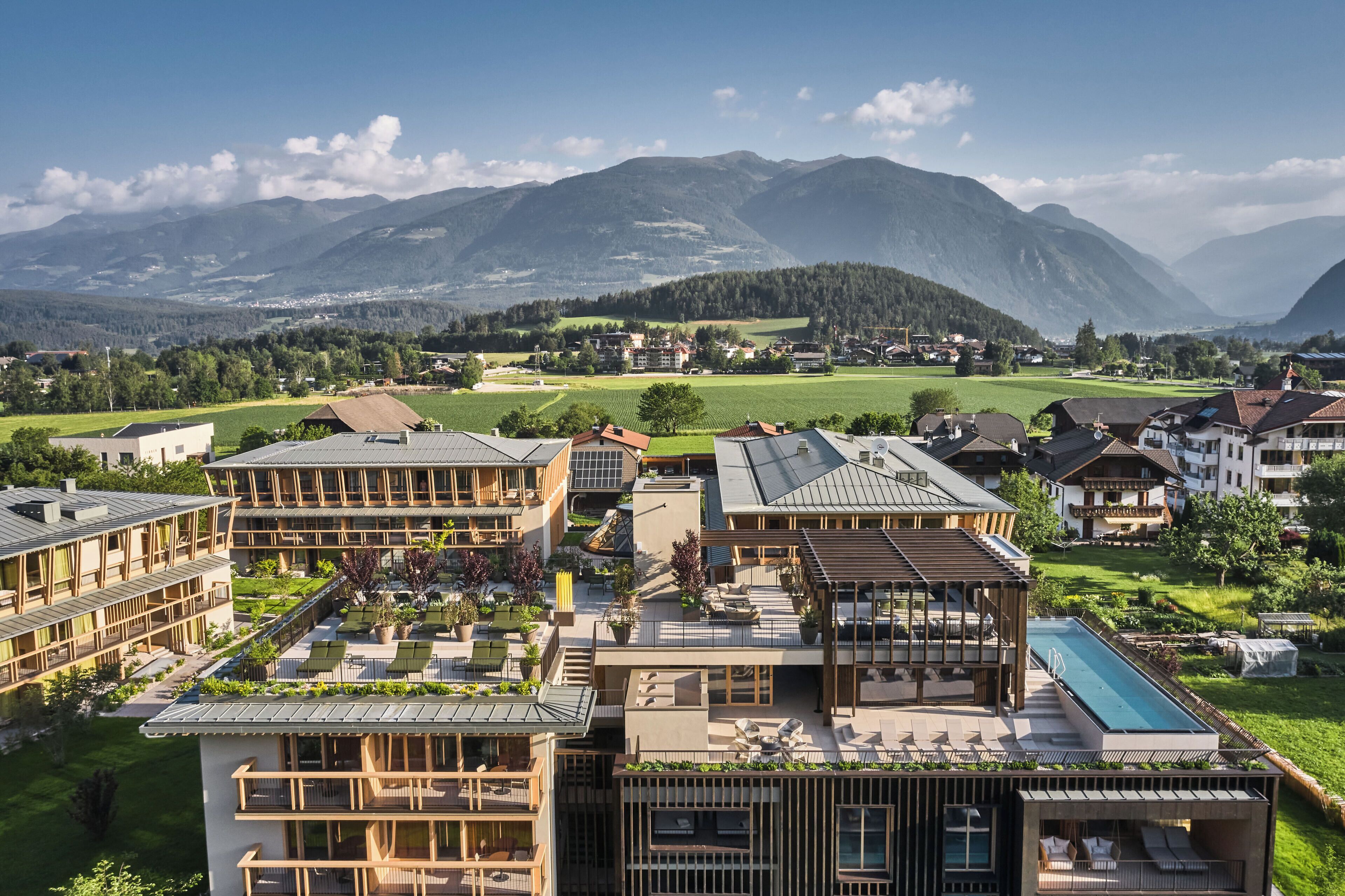 A residential area with modern buildings, a swimming pool, and a view of mountains.