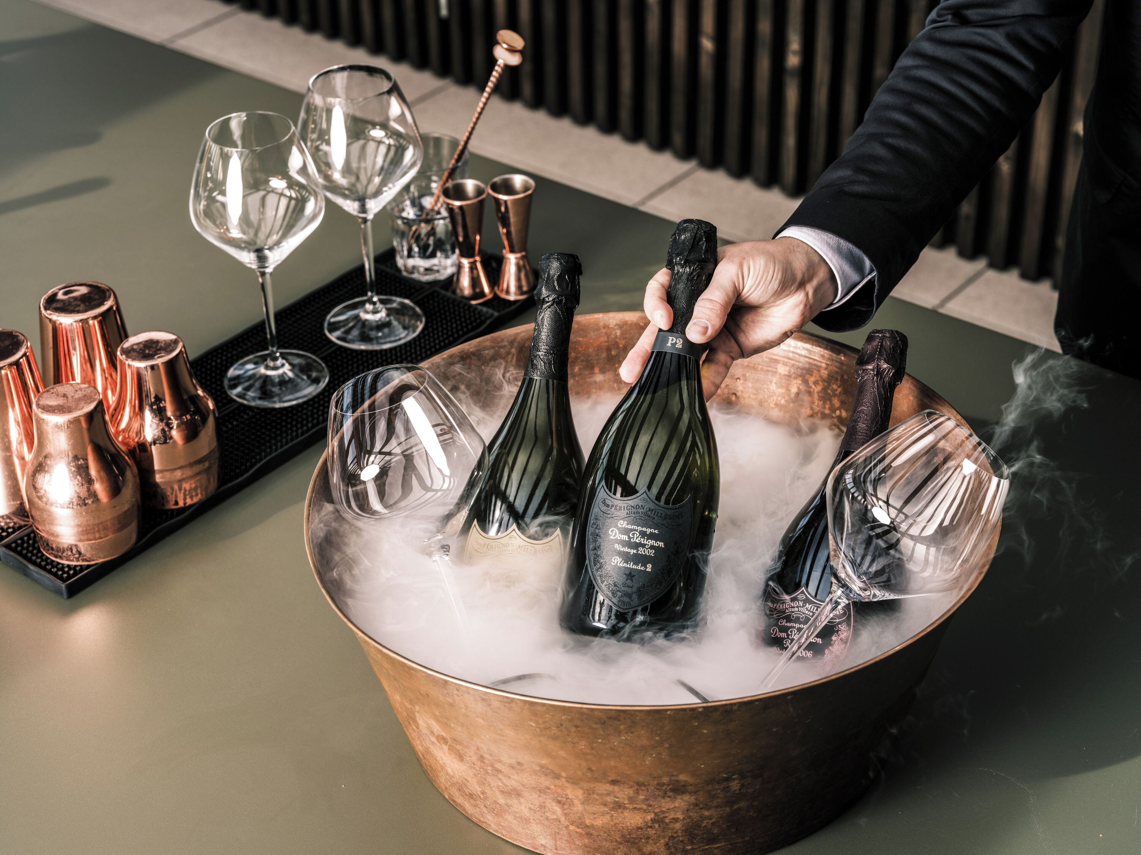 A copper bucket filled with ice, champagne bottles, and wine glasses.