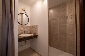 Un bagno con lavandino, specchio e zona doccia.