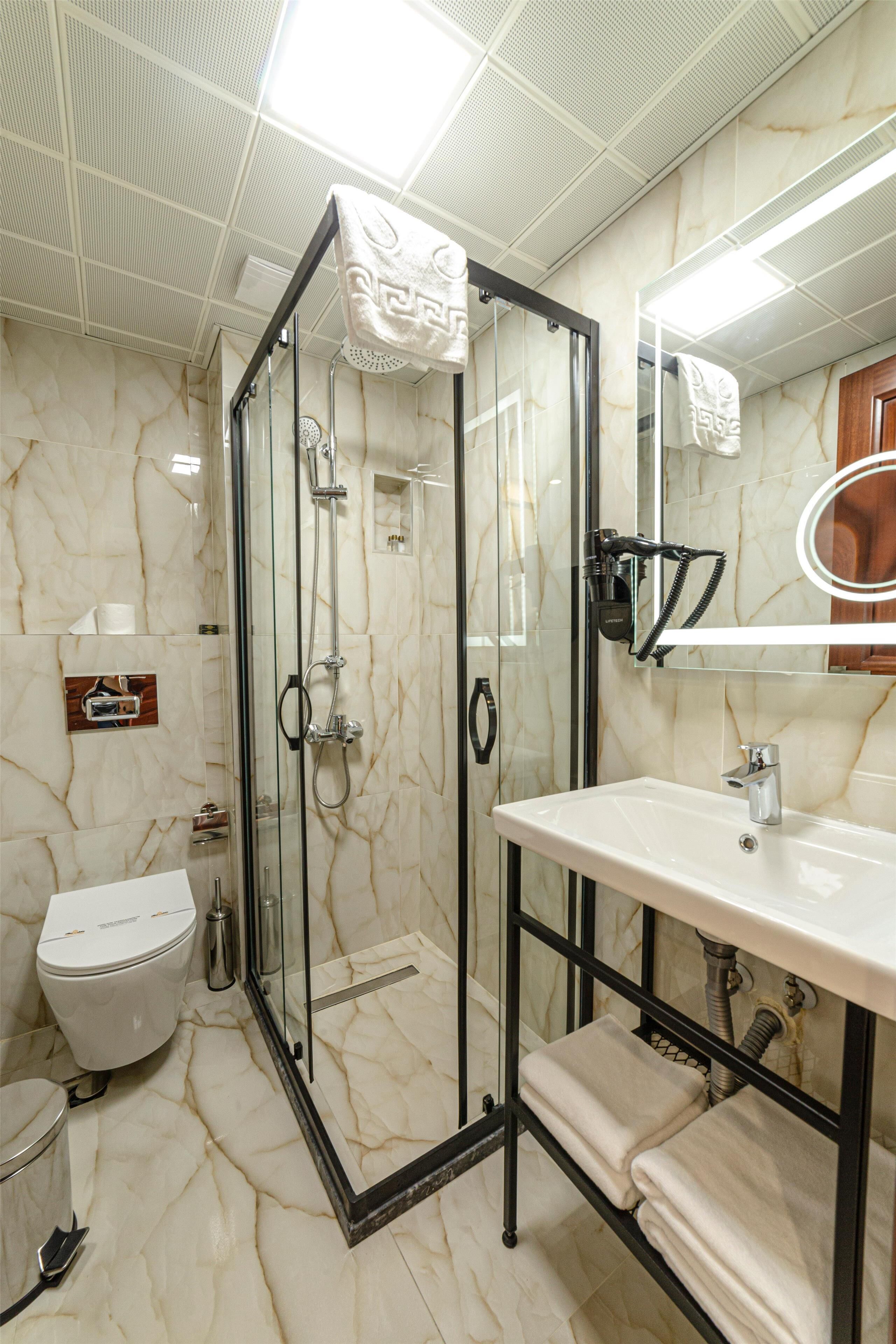 Een badkamer met een douchecabine van glas, een wit wastafelmeubel en een spiegel met houten lijst.