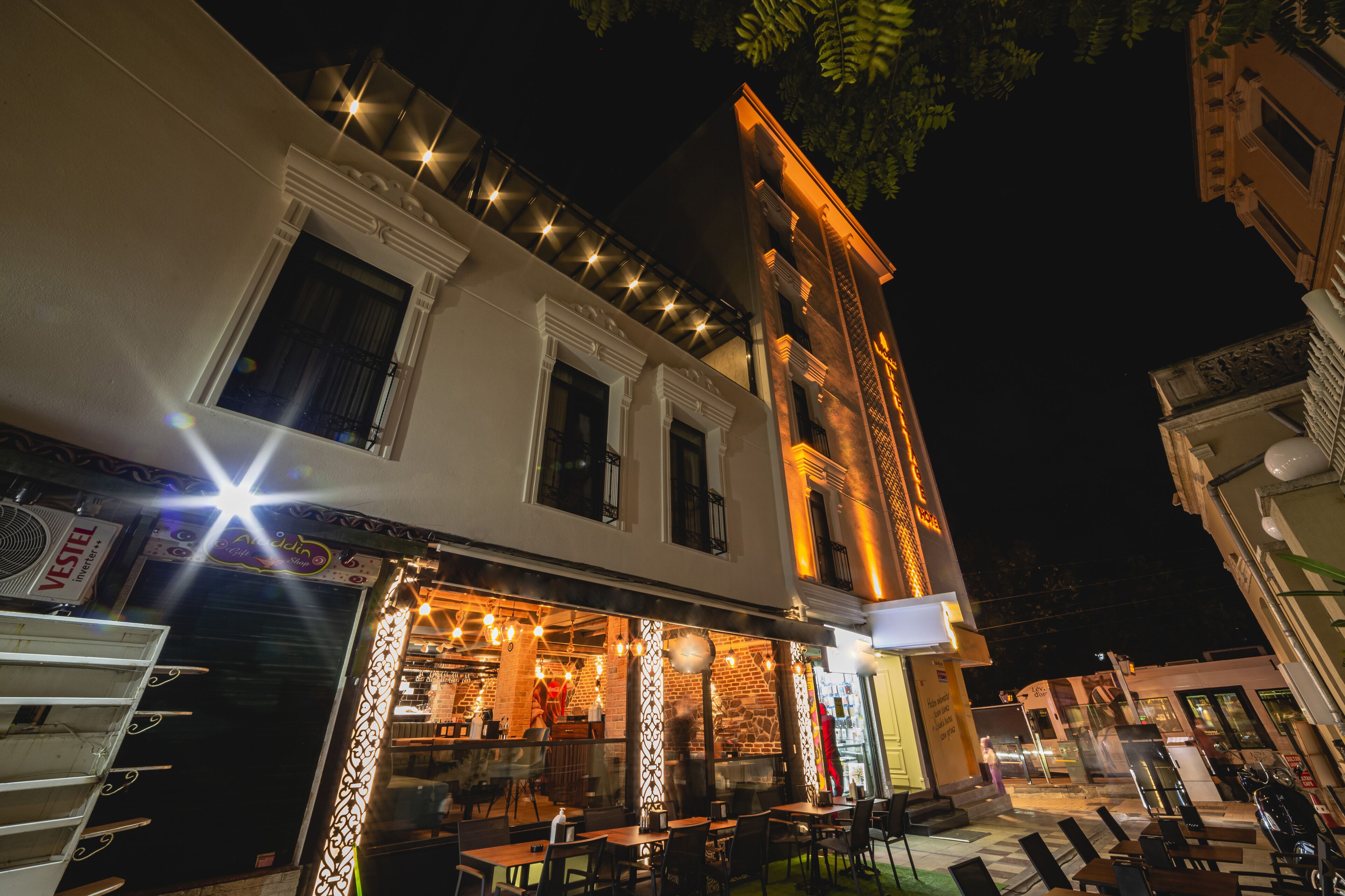 A restaurant with outdoor seating, a brick building facade, and string lights.