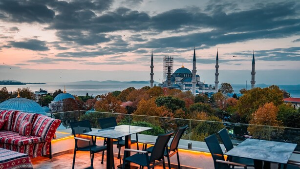 A terrace with outdoor seating and a view of a mosque with two minarets. - World Heritage Center Hotel (Istanbul)