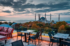 Una terraza con asientos al aire libre y vistas a una mezquita con dos minaretes.