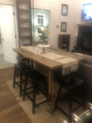 A dining area with a wooden table, two chairs, a vase with flowers, and a television on the wall. - Secluded, Cozy Cottage in the Shenandoah Valley (Maurertown)