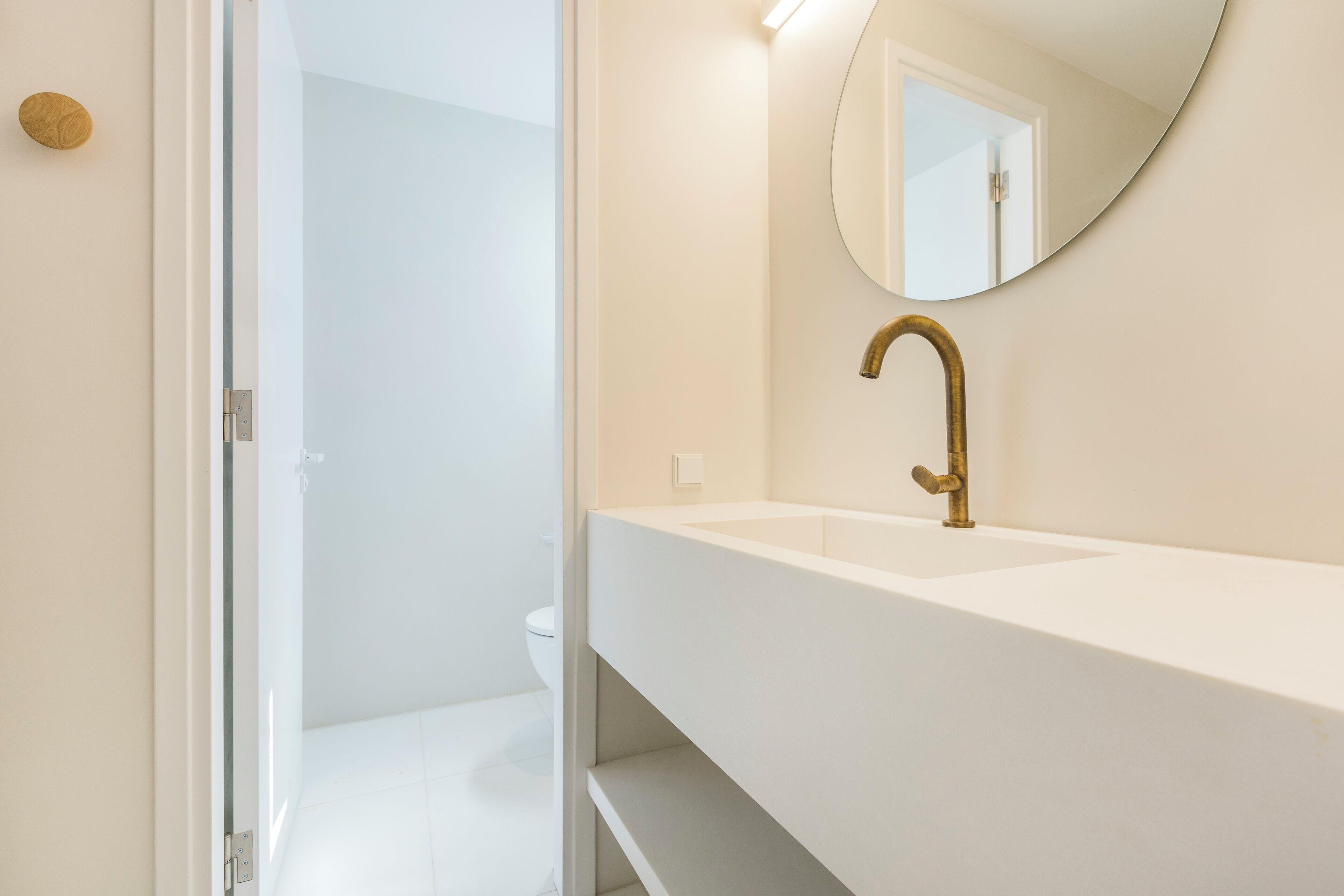 A bathroom with a white sink, a gold faucet, and a mirror.