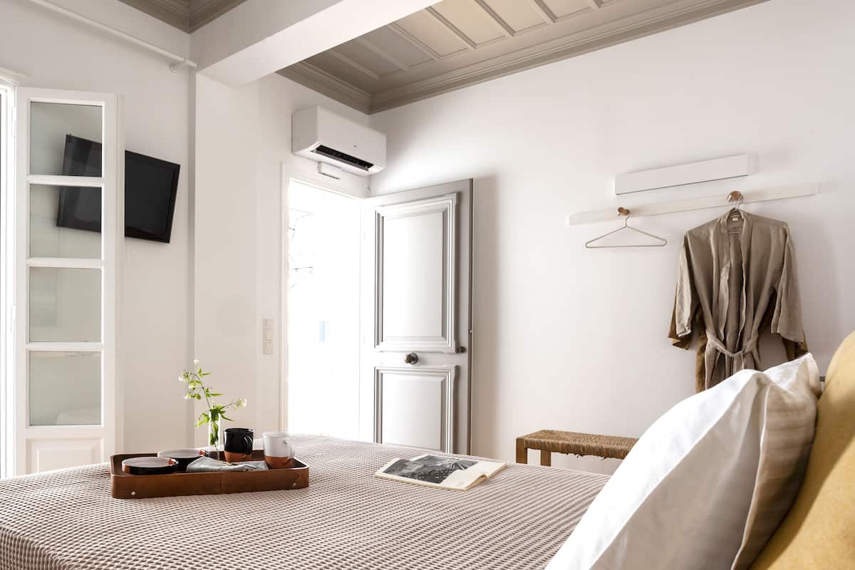A neatly arranged bedroom with a bed, bedside table, and a hanging garment rack.
