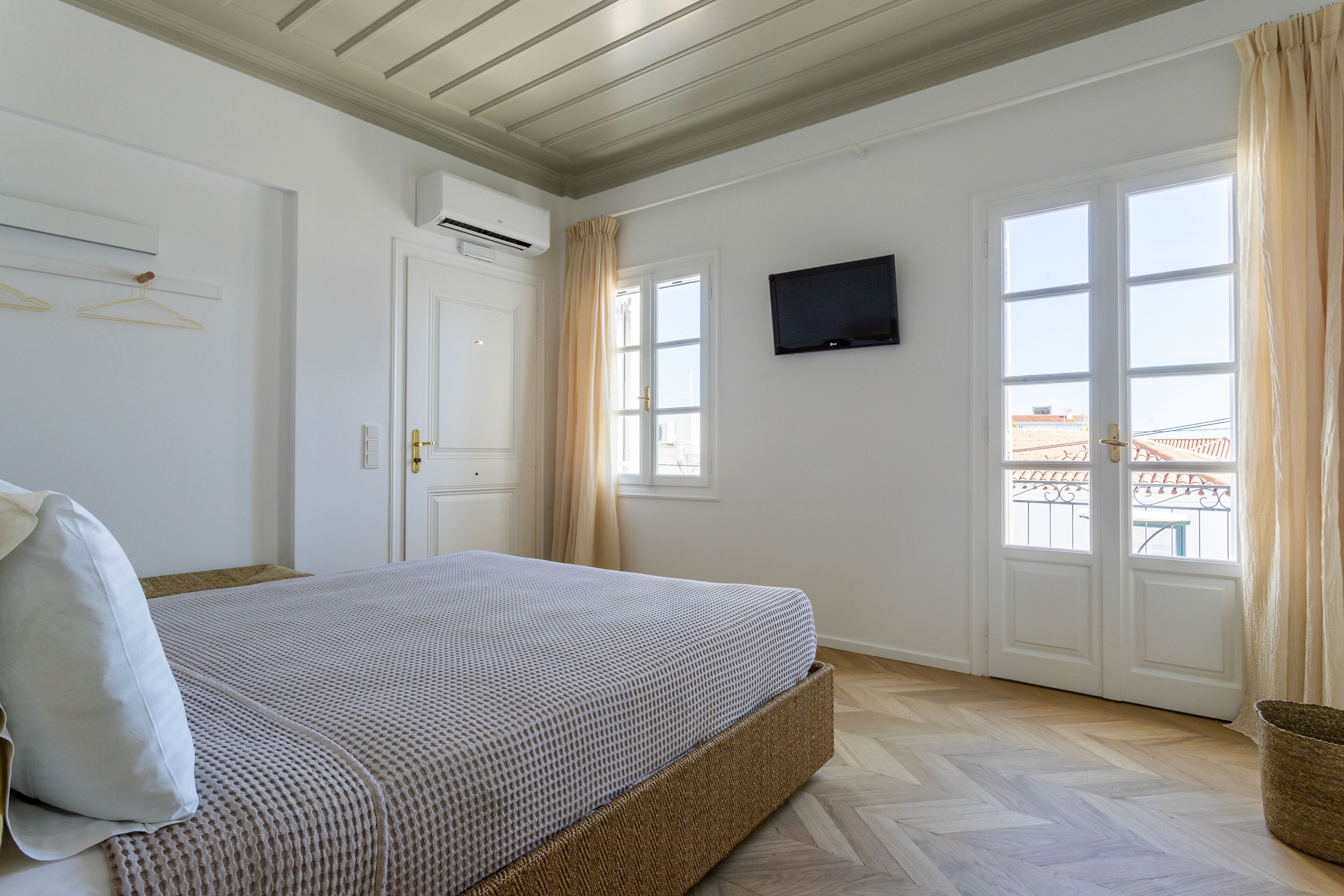 Ein Schlafzimmer mit Bett, Fernseher und einem fensterbepflanzten Fenster.