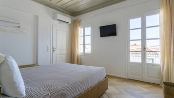 Ein Schlafzimmer mit Bett, Fernseher und einem fensterbepflanzten Fenster.