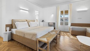 Une chambre moderne avec un grand lit, un banc, un bureau et une vue sur l’extérieur.