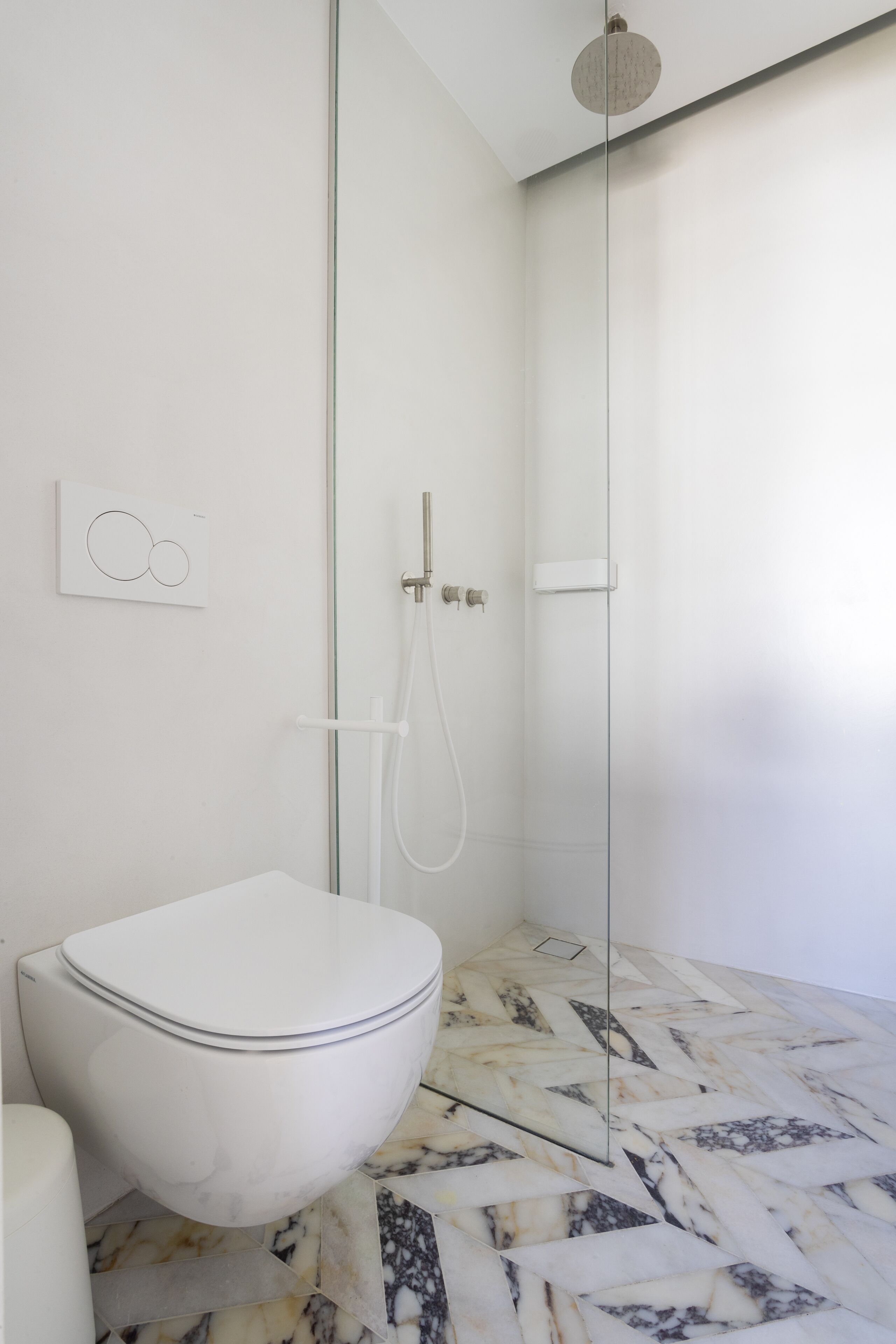 A modern bathroom with a toilet, shower, and marble floor.