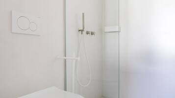 A modern bathroom with a toilet, shower, and marble floor.