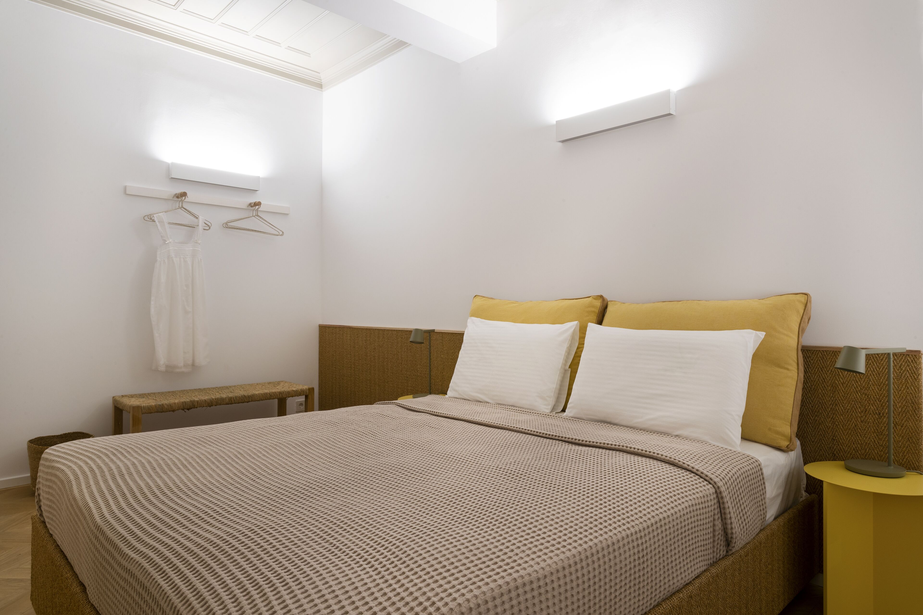 Un dormitorio con cama, mesita de noche y lámpara colgante.