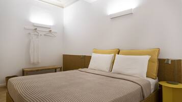 Un dormitorio con cama, mesita de noche y lámpara colgante.