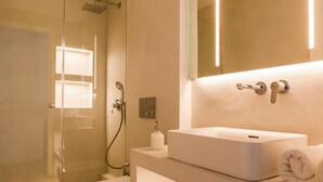 Une salle de bain moderne avec une douche à parois de verre, un lavabo blanc et un grand miroir.