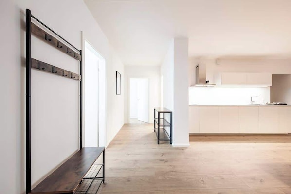 A modern kitchen with white cabinets, a wooden bench, and a metal rack on the wall.