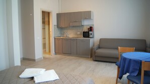 A compact room with a bed, a small kitchenette, a sofa, and a table. - Hotel Sogno (Viareggio)