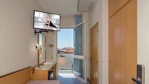 A hotel room with a bed, a television mounted on the wall, a desk with a telephone, and a sliding glass door leading to a balcony. - Hotel Sogno (Viareggio)