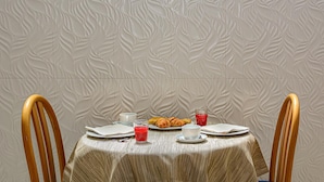 A dining table set with plates, cups, and a glass of red juice. - Hotel Sogno (Viareggio)