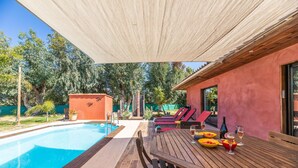 A poolside area with a wooden table set for dining, a pool, and lounge chairs.