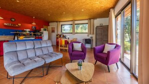 A modern living room with a grey sofa, two purple armchairs, and a wooden coffee table.