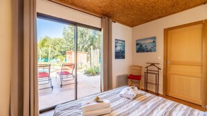 A bedroom with a large sliding glass door leading to an outdoor area with a pool and chairs.