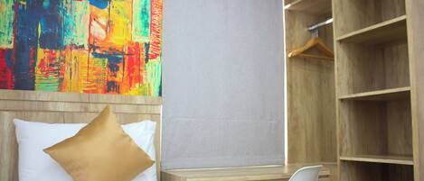 Una habitación de hotel con cama, escritorio, silla y armario.
