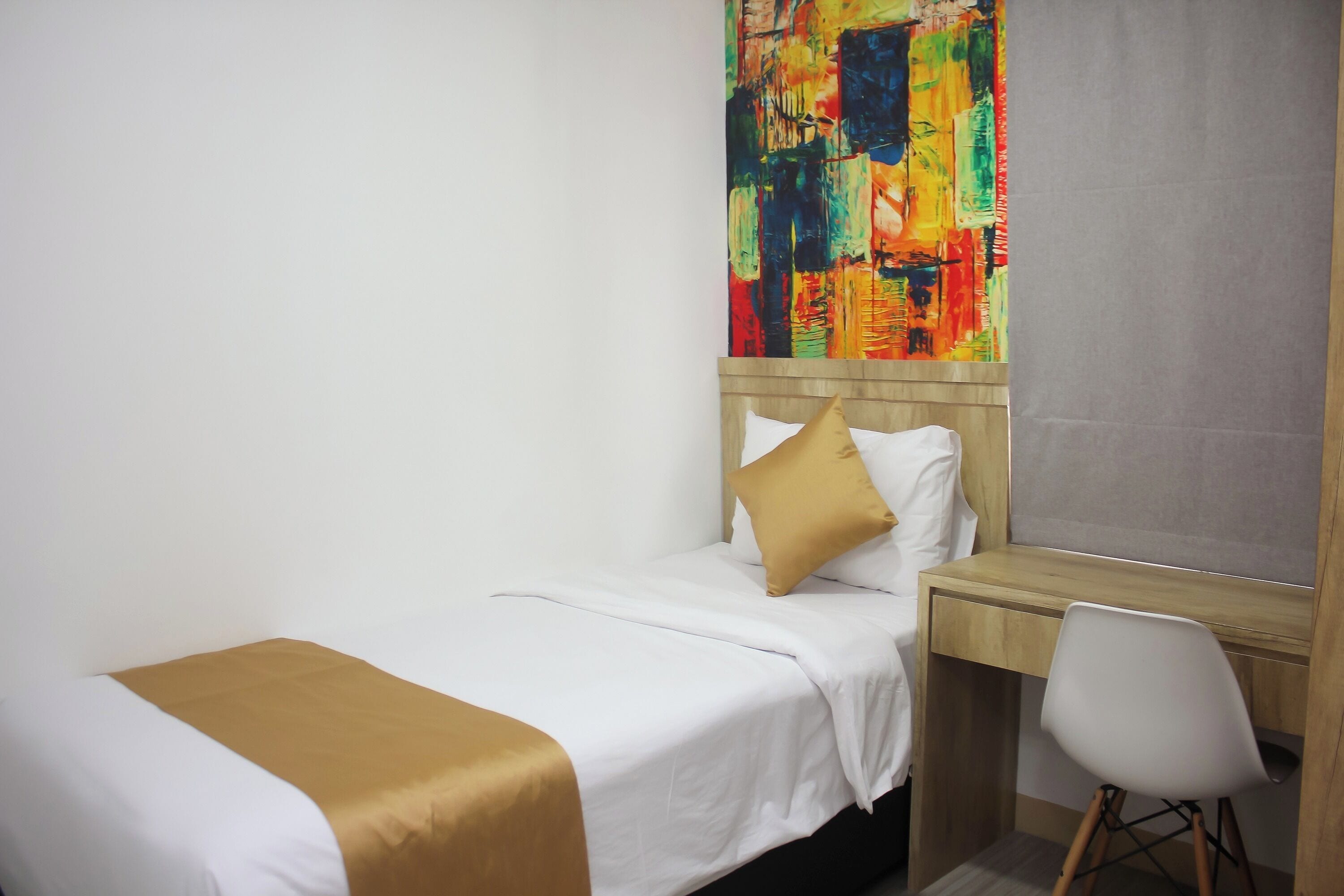 Una camera d'albergo con un letto, una scrivania e una sedia.