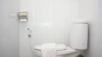 Un bagno moderno con un water, un dispenser di carta assorbente e un rotolo di carta igienica.