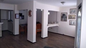 A spacious living area with a wooden floor, a kitchen area with a refrigerator, and a dining area with a table and chairs.