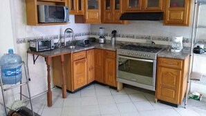 A compact kitchen with wooden cabinets, a microwave, a stove, and a sink.
