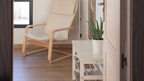 A room with a wooden floor, a white chair, a desk with a plant, and a hanging clothes rack. - Alojamiento Rural "La Moravieta" (Pozoamargo)