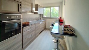 Eine moderne Küche mit eingebauten Geräten, einem großen Fenster und einer Bar.