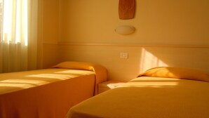 Una stanza con due letti, ognuno dotato di testiera e comodino.