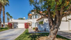 A two-story house with a front driveway, palm trees, and a well-maintained lawn. - 2 bedroom spacious Condo (Palm Desert)