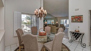 A dining area with a glass table, chairs, a chandelier, and a wine rack. - 2 bedroom spacious Condo (Palm Desert)