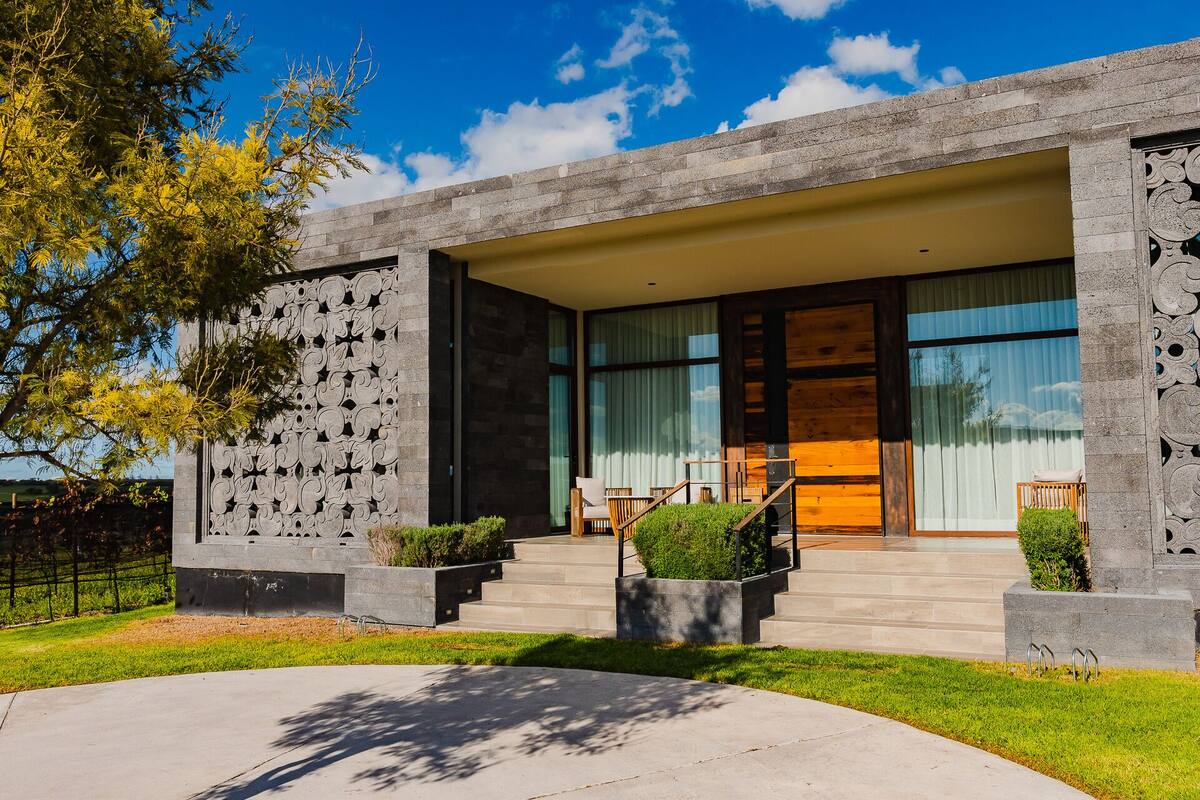 A modern building with a stone facade, large windows, and a well-maintained lawn.