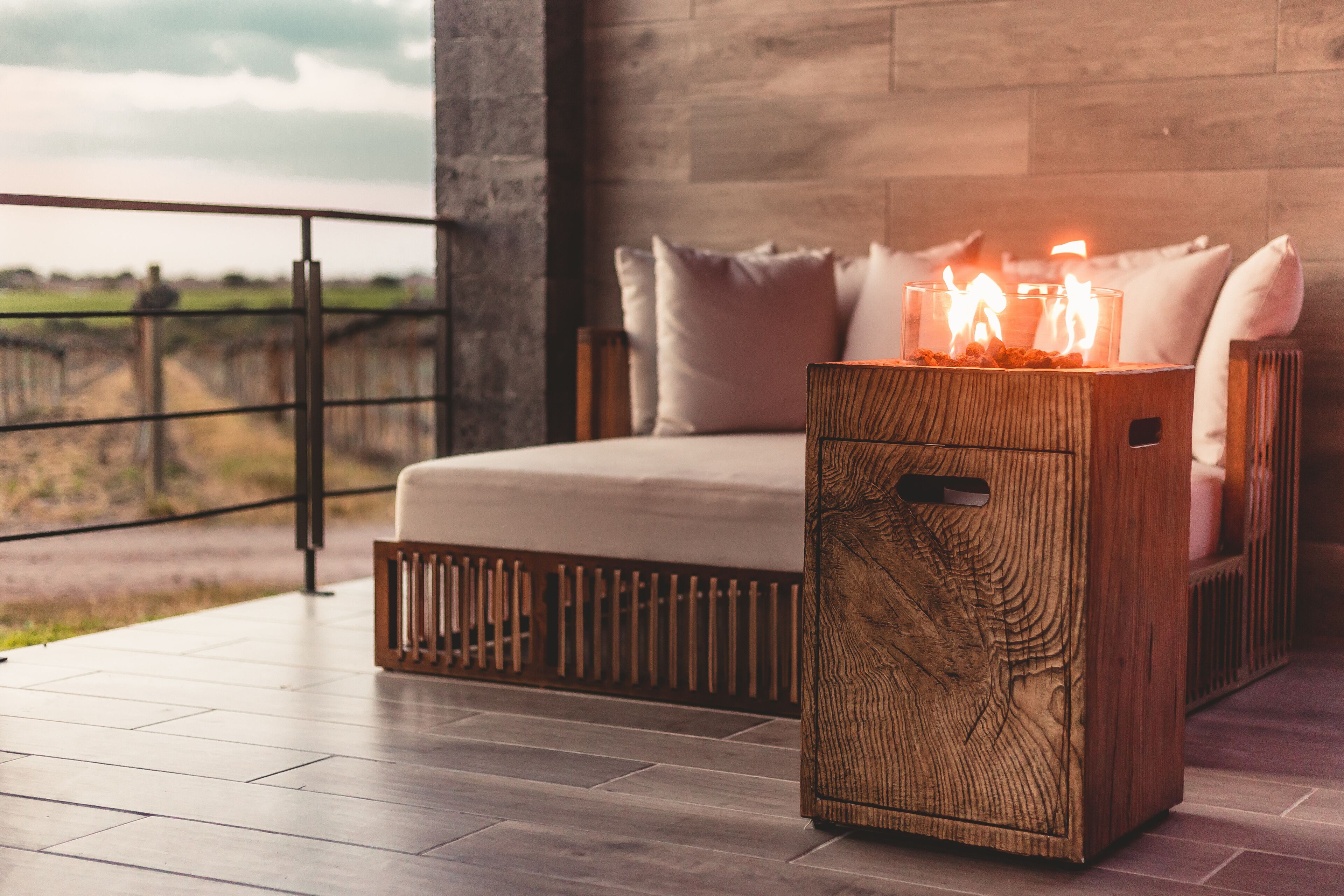 Une chambre à coucher moderne avec une grande fenêtre, une table de chevet en bois ornée de bougies et une vue sur la campagne.