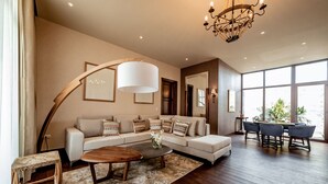 A modern living room with a sectional sofa, a coffee table, and a dining area with a table and chairs. - Hotel Boutique Tres Raíces (Dolores Hidalgo)