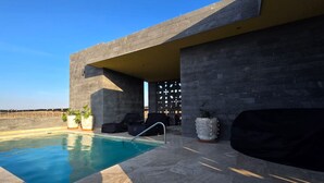 A poolside area with a concrete structure, seating, and potted plants. - Hotel Boutique Tres Raíces (Dolores Hidalgo)