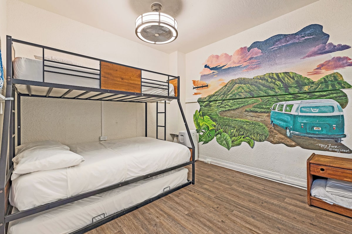 Une chambre avec des lits superposés, dont un mur est décoré d’une fresque représentant un fourgon et des montagnes.